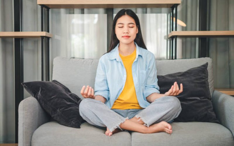 young woman student wearing headphones is relaxing during long online classes, distance learning on the couch at home